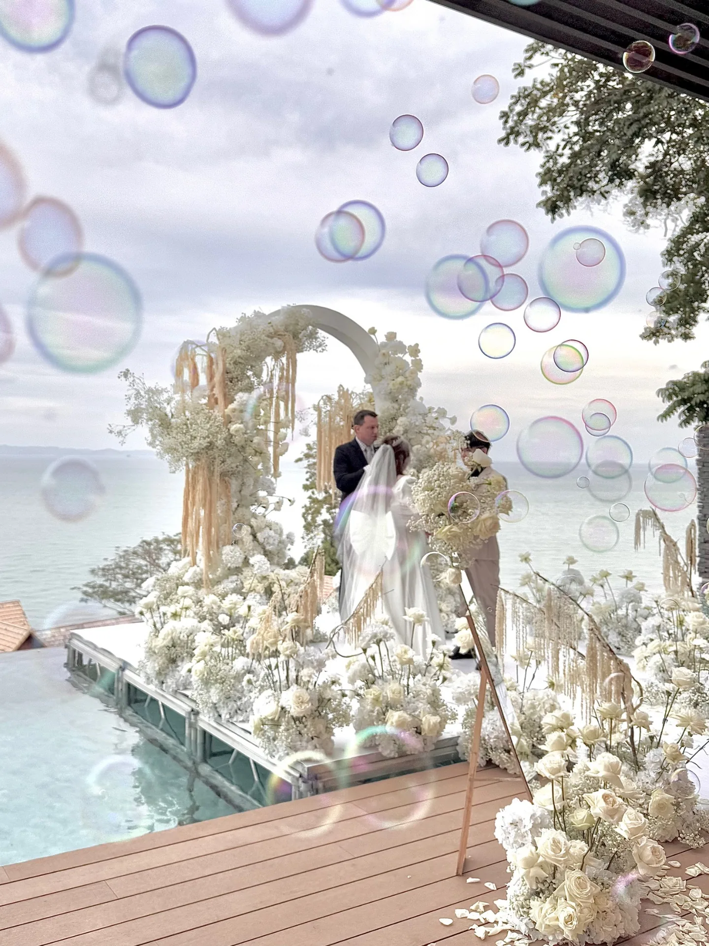 Seaside white floral arch ceremony with bubbles