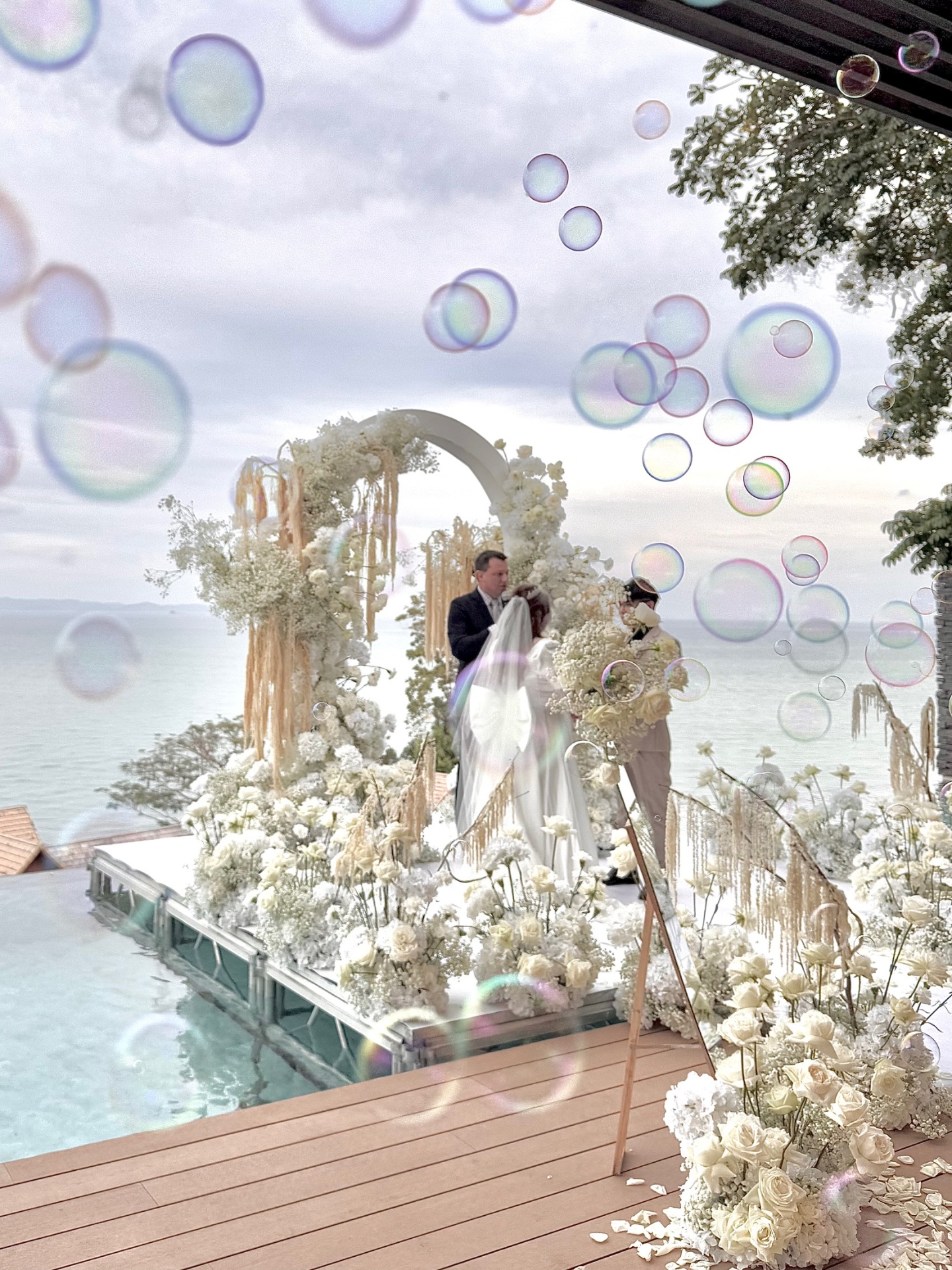 Seaside white floral arch ceremony with bubbles